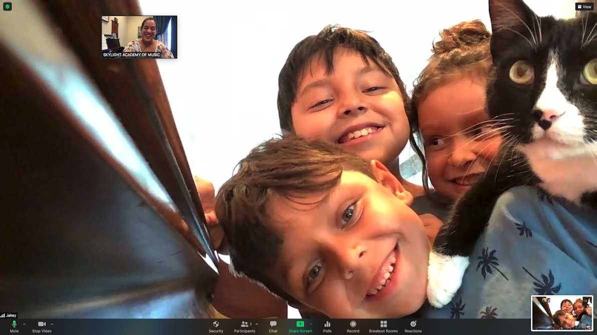 Smiling family of children and their cat during an online Skylight music lesson break, enjoying their time and having fun